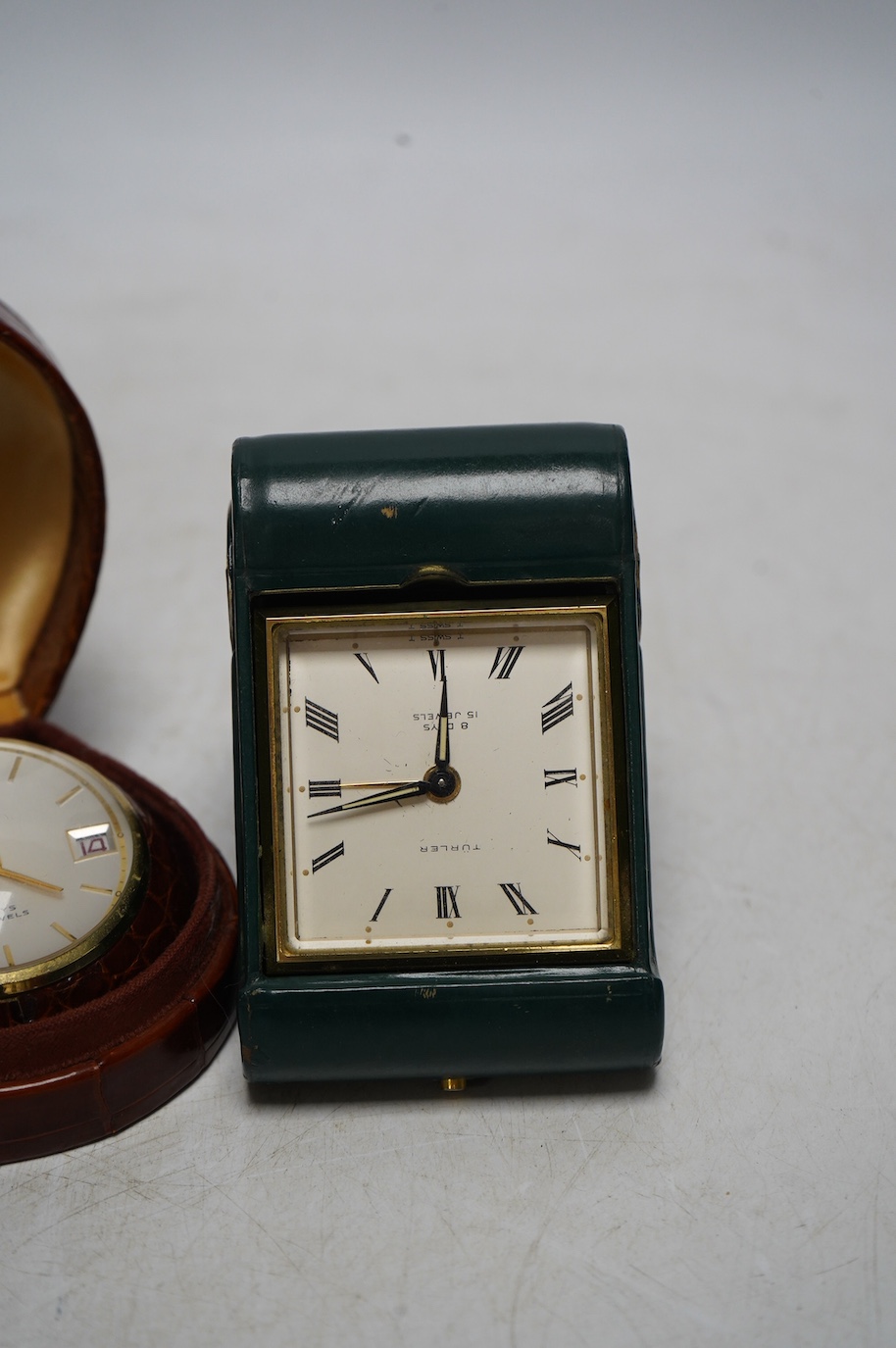 A Turler crocodile cased travelling alarm timepiece and another in green leather. Condition - green case a little scuffed, both wind and are currently ticking but not guaranteed